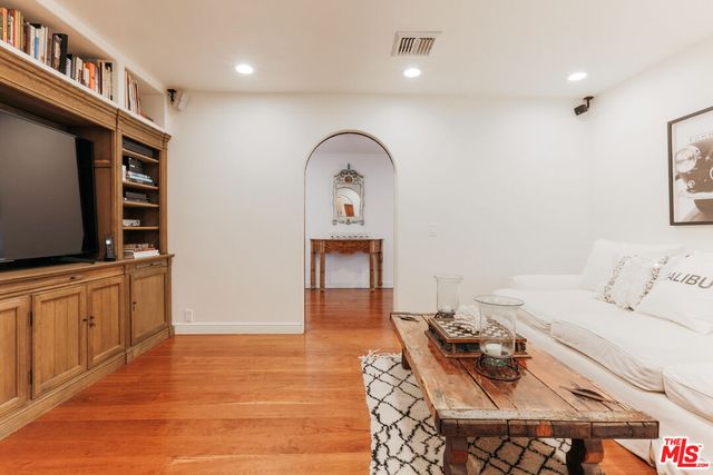 a living room with furniture a flat screen tv and a refrigerator