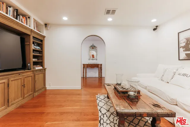a living room with furniture a flat screen tv and a refrigerator