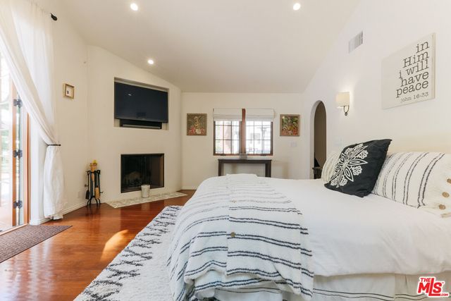 a spacious bedroom with a bed and a flat screen tv