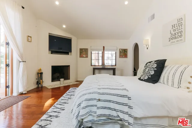a spacious bedroom with a bed and a flat screen tv
