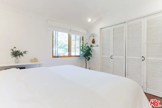 a bedroom with a large bed and a potted plant