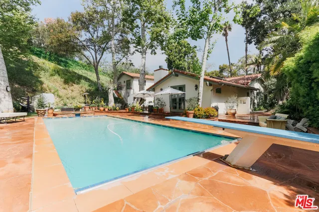 a view of a swimming pool with a lawn chairs under an umbrella