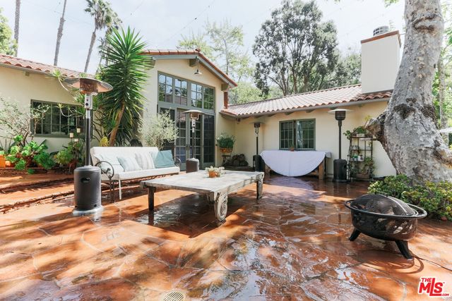 a view of a patio with table and chairs potted plants and a large tree