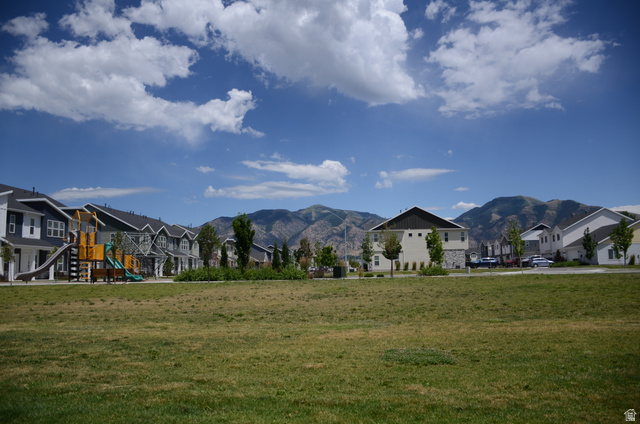 1842 South 1280th Street West Logan, UT 84321 - Photo 21 of 21 Expansive green space with mature landscaping, surrounded by multi-story residential buildings featuring varied siding materials and dark-toned roofs
