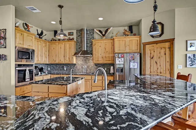 an open kitchen with granite countertop a stove and white cabinets with wooden floor