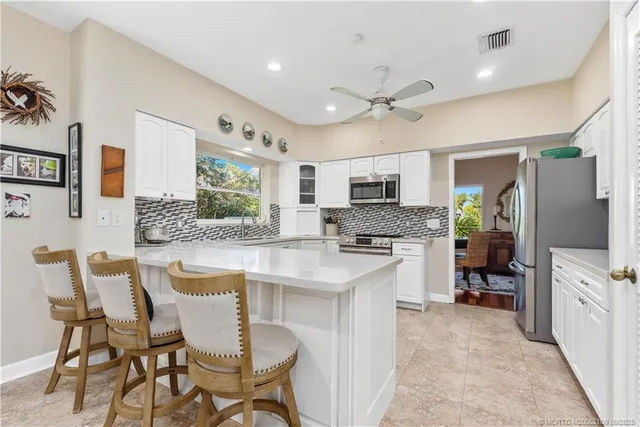 a kitchen with granite countertop white cabinets stainless steel appliances a sink and a large window