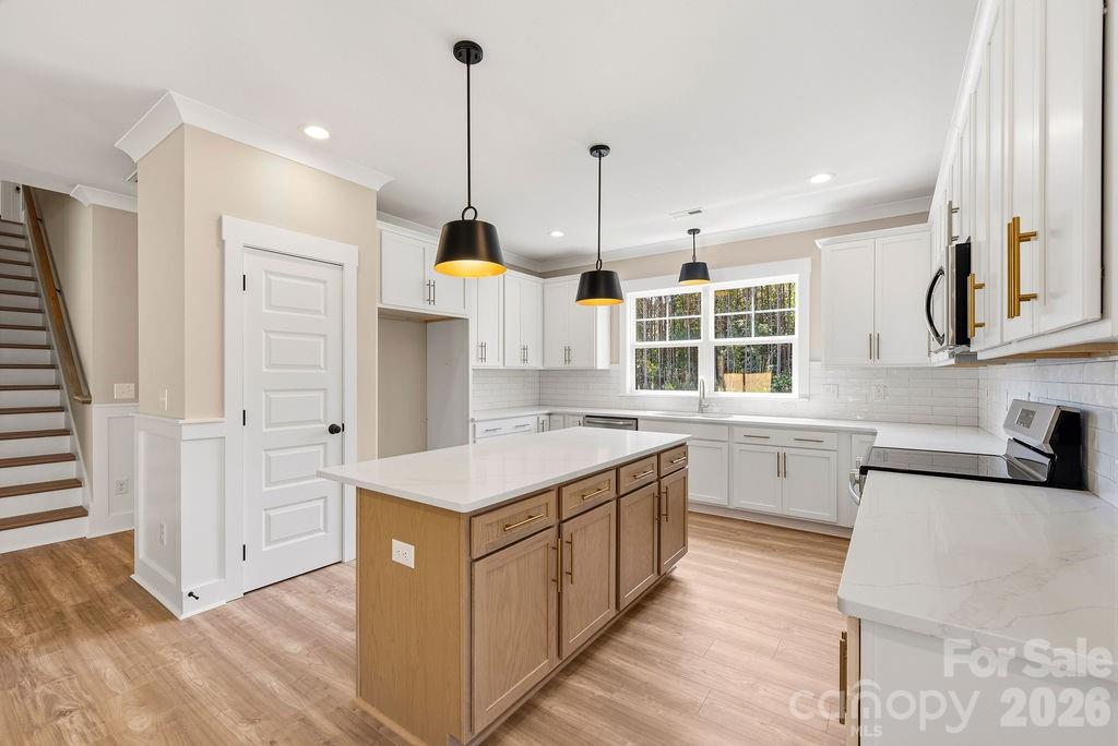 1020 Baylor Grove Road, Unit 20 Monroe, NC 28112 - Photo 21 of 45 a kitchen with stainless steel appliances granite countertop a sink a stove and a wooden floor