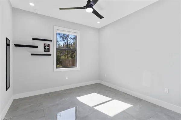 an empty room with windows and ceiling fan