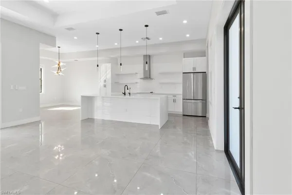 a large white kitchen with a refrigerator a sink dishwasher and a view of kitchen