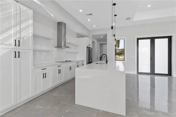 a large white kitchen with wide window and stainless steel appliances