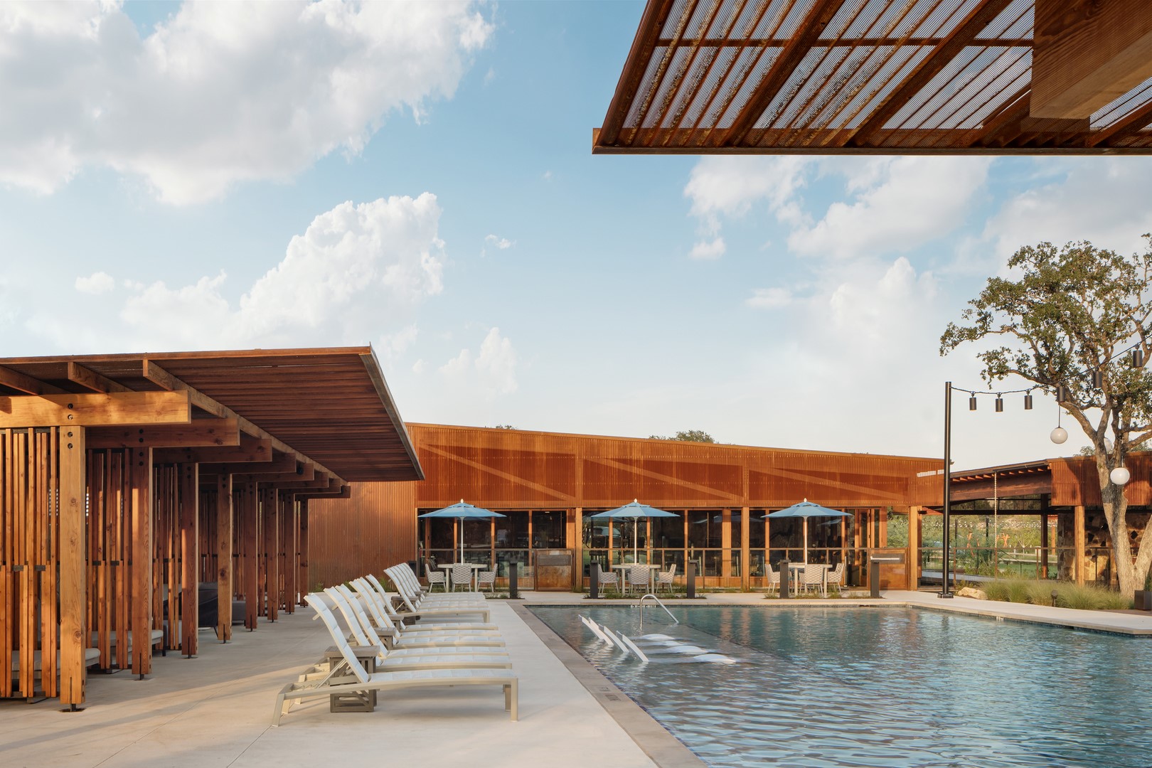 A pristine pool area awaits, flanked by a contemporary wood-slatted structure and comfortable lounge seating.