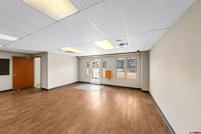 a view of a room with wooden floor ceiling fan and windows
