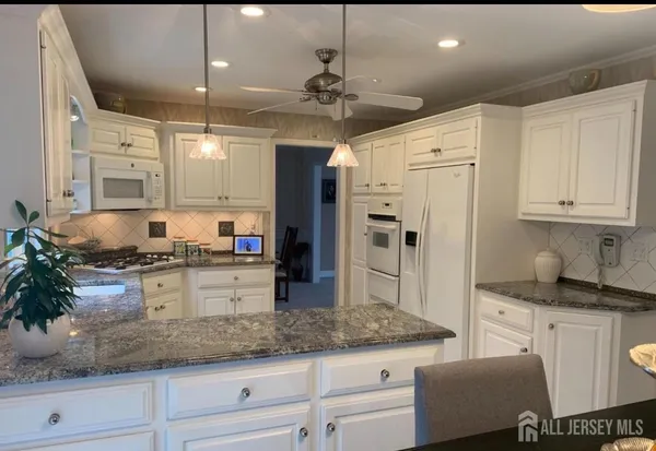 a kitchen with granite countertop a sink a counter space appliances and cabinets