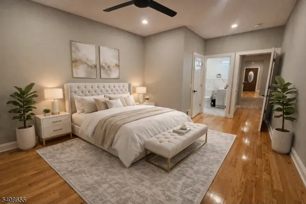 a spacious bedroom with a bed a couch and potted plant with the wooden floor