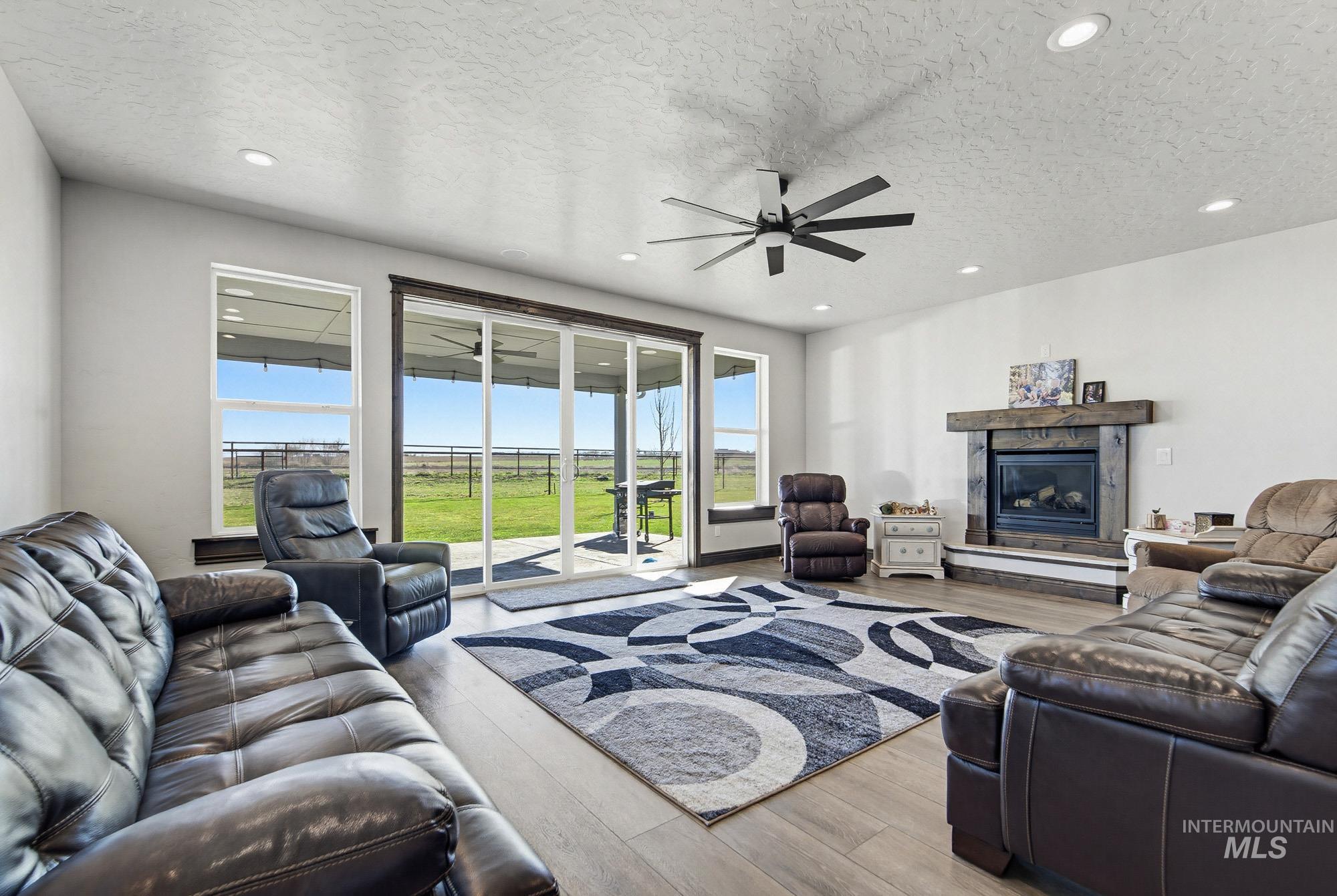 24753 Simplot Boulevard Wilder, ID 83676 - Photo 13 of 47 Living room with wood finished floors, a textured ceiling, a fireplace, a ceiling fan, and recessed lighting