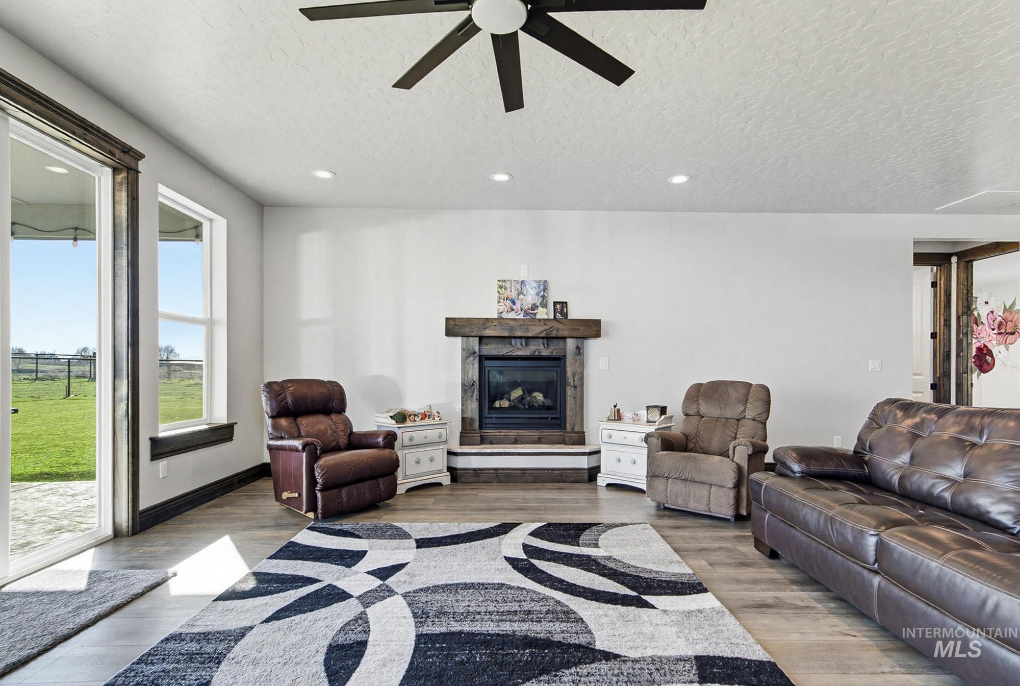 24753 Simplot Boulevard Wilder, ID 83676 - Photo 14 of 47 Living room with a textured ceiling, a fireplace, a ceiling fan, light wood-type flooring, and recessed lighting