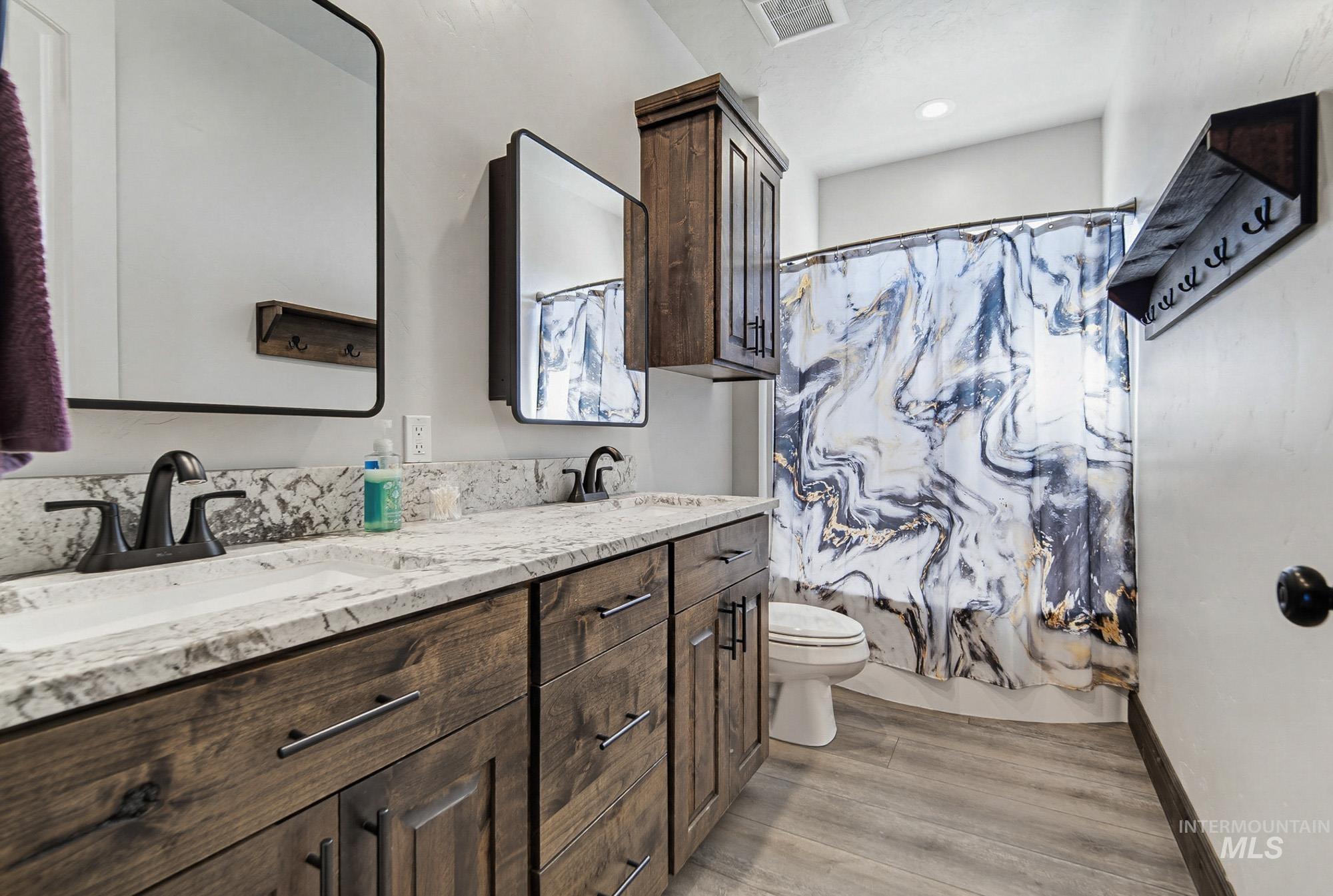 24753 Simplot Boulevard Wilder, ID 83676 - Photo 30 of 47 Full bathroom with double vanity, light wood-style floors, and shower / tub combo with curtain