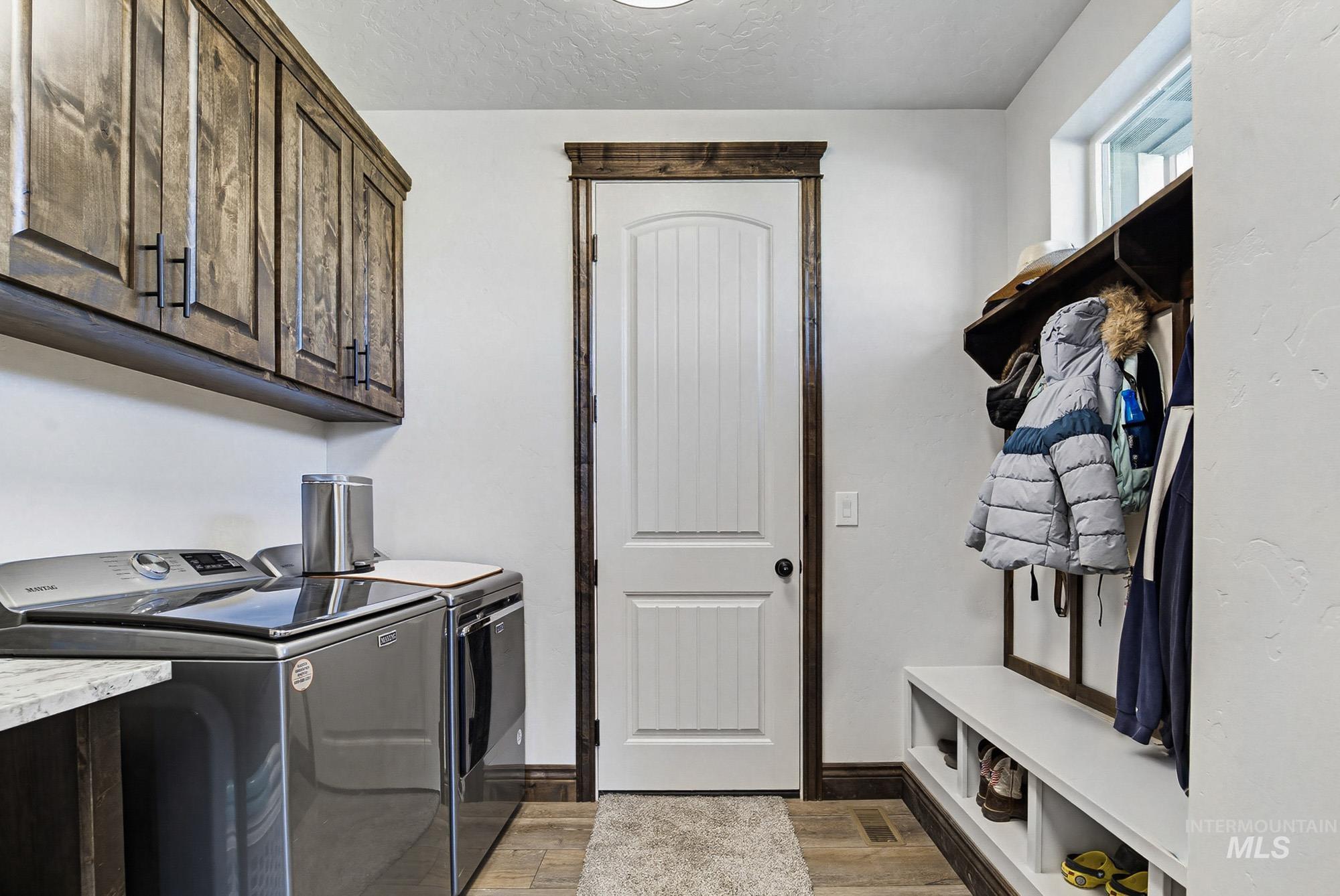 24753 Simplot Boulevard Wilder, ID 83676 - Photo 32 of 47 Laundry area featuring light wood-style flooring, a textured ceiling, washing machine and dryer, and cabinet space
