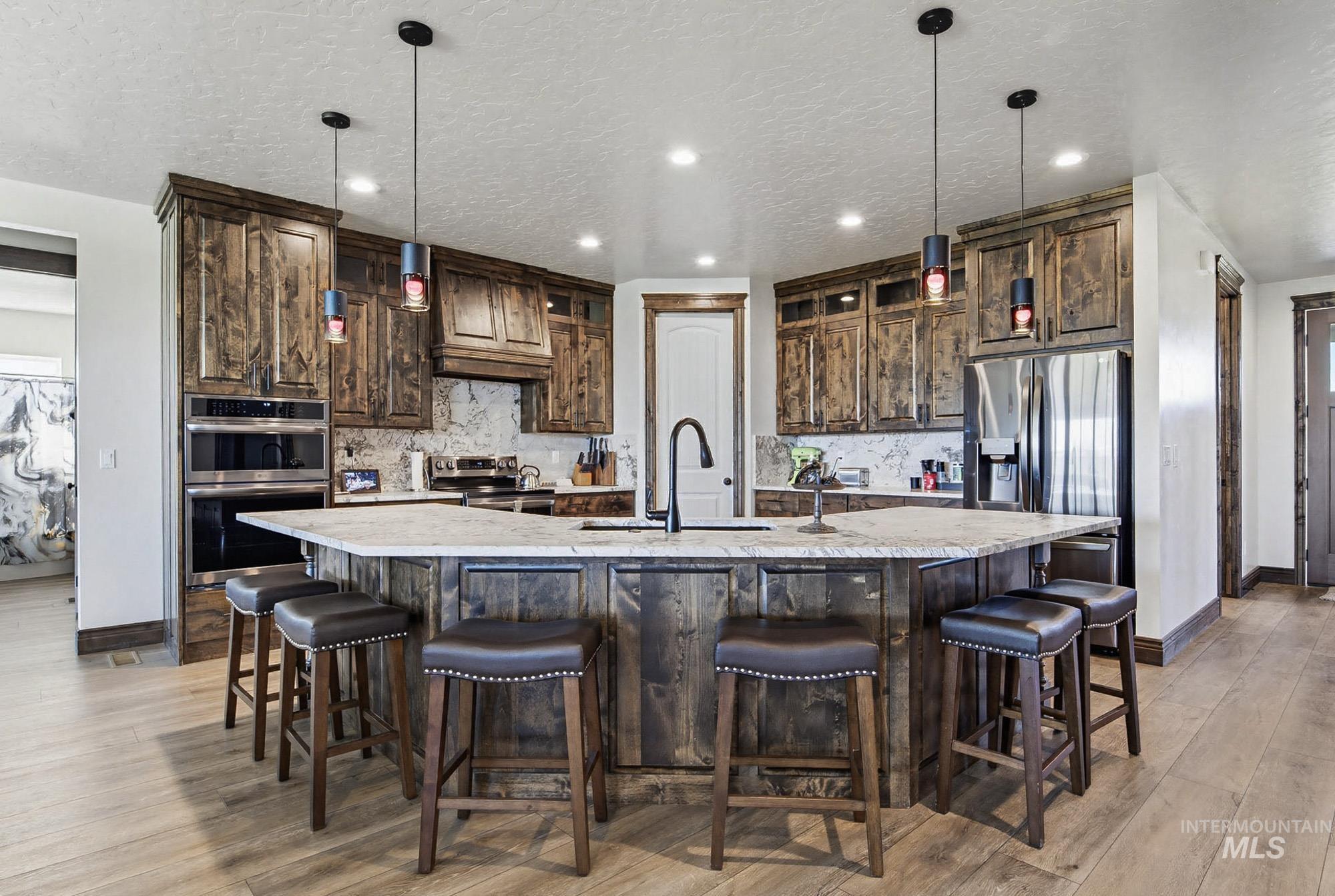 24753 Simplot Boulevard Wilder, ID 83676 - Photo 8 of 47 Kitchen featuring dark wood finish cabinetry, a breakfast bar, decorative backsplash, and a textured ceiling