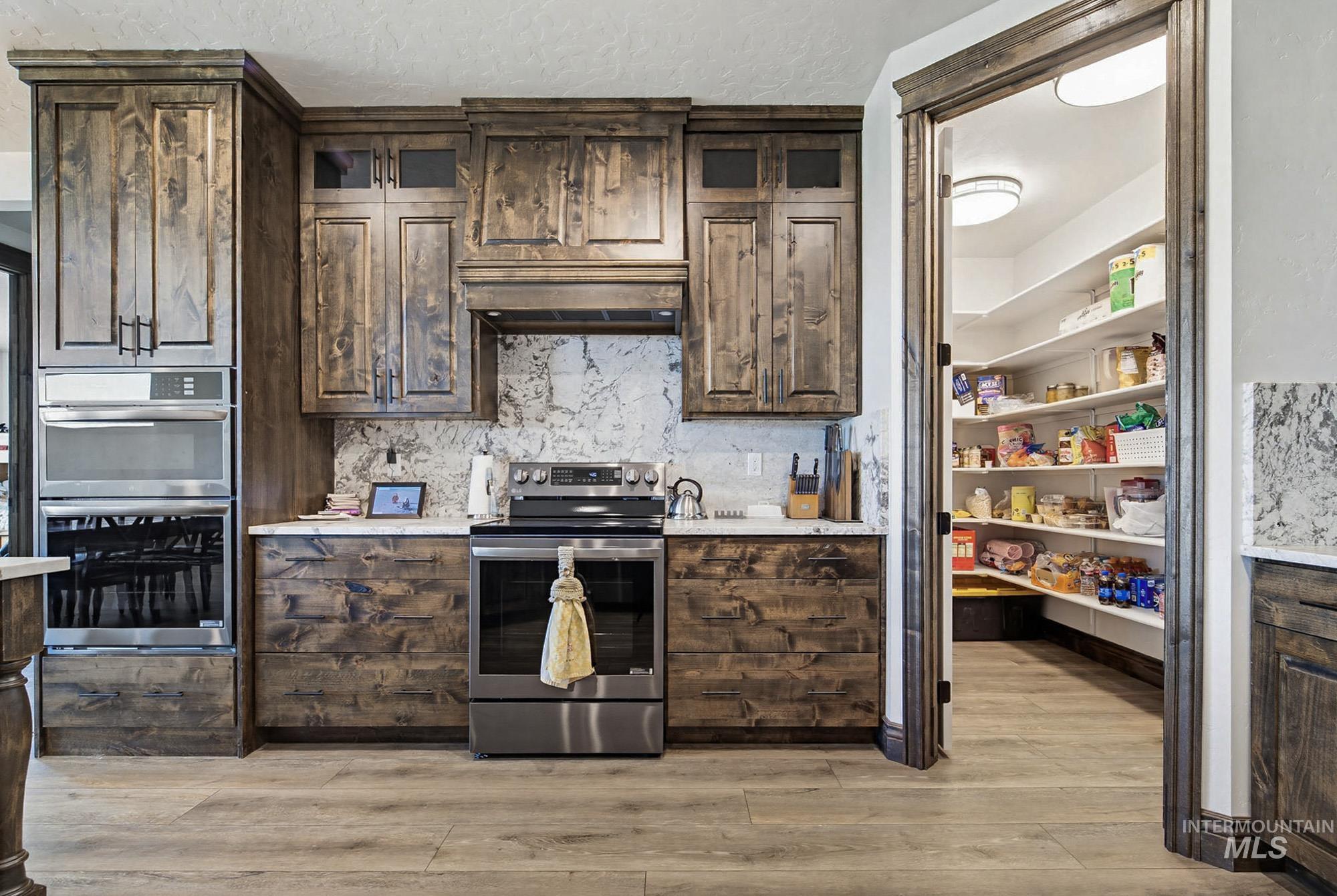 24753 Simplot Boulevard Wilder, ID 83676 - Photo 9 of 47 Kitchen with dark wood finish cabinetry, stainless steel appliances, backsplash, and light wood finished floors