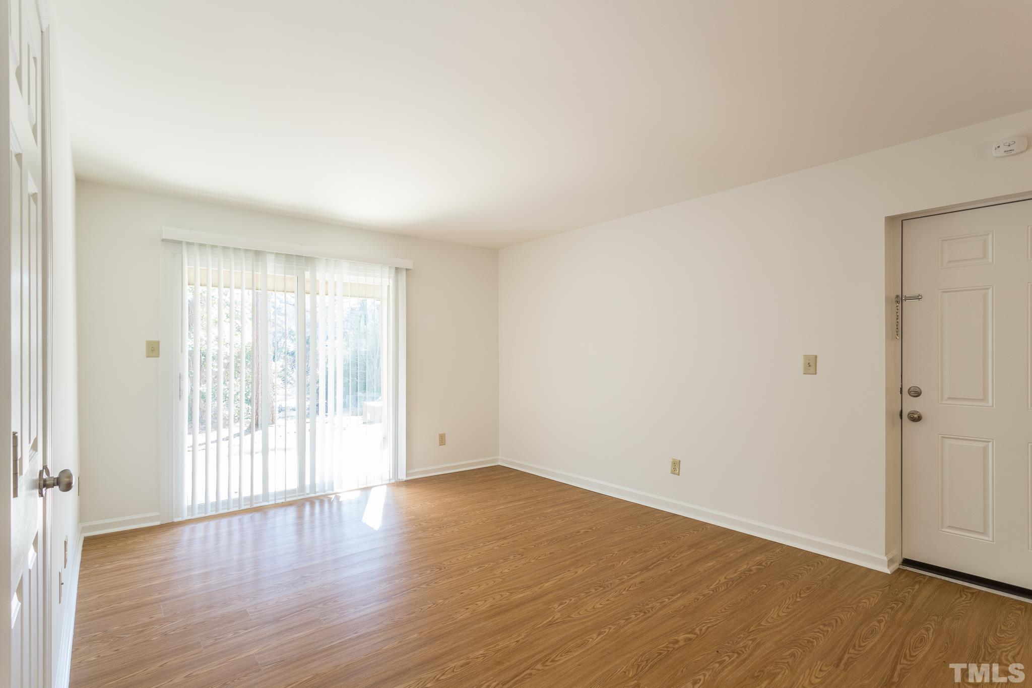 608 Pine Ridge Place, Unit NONE Raleigh, NC 27609 - Photo 8 of 16 a view of an empty room with wooden floor and a window