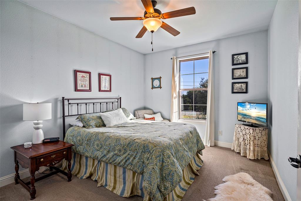 1177 Ronald Road Glen Rose, TX 76043 - Photo 22 of 30 a bedroom with a bed and a chandelier