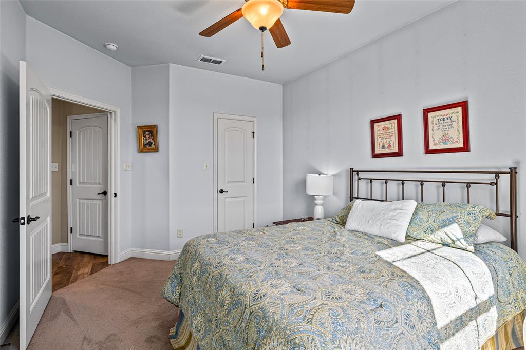 1177 Ronald Road Glen Rose, TX 76043 - Photo 23 of 30 a bedroom with a large bed and a chandelier