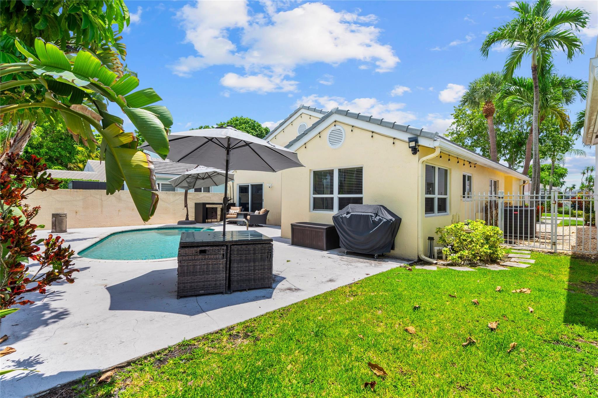 7904 Travelers Tree Drive Boca Raton, FL 33433 - Photo 16 of 35 a patio with table and chairs under an umbrella