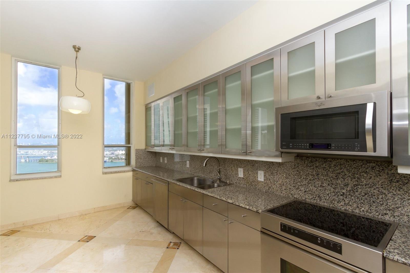 888 Brickell Key Drive, Unit PH2802 Miami, FL 33131 - Photo 9 of 47 a kitchen with granite countertop a stove a sink and a microwave