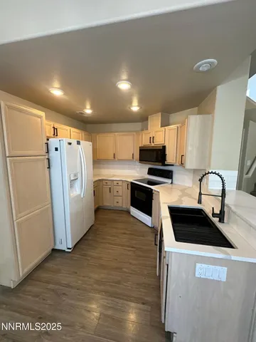 a kitchen with granite countertop a refrigerator stove and sink