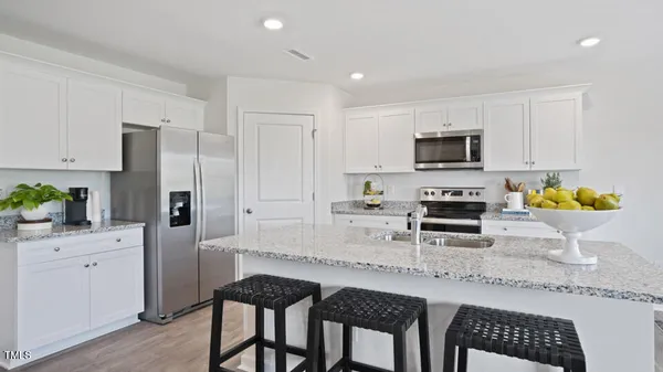a kitchen with a sink a refrigerator and chairs