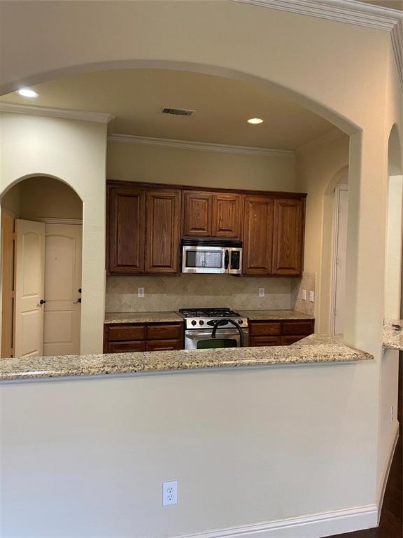 2222 Kirby Street Dallas, TX 75204 - Photo 22 of 25 Kitchen featuring a granite-topped pass-through, wood cabinetry, stainless steel microwave, and gas range