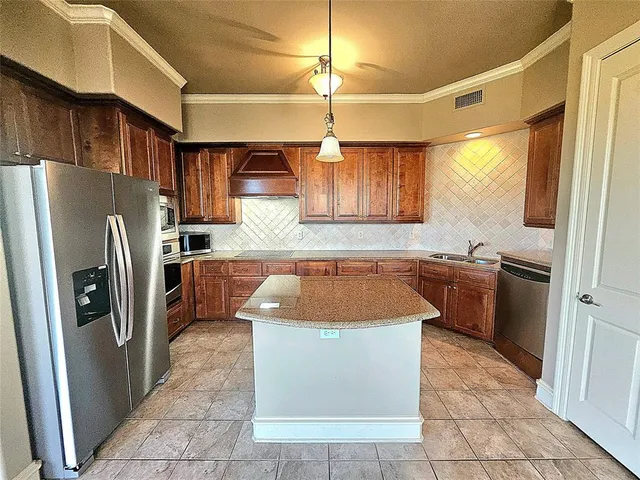 a kitchen with stainless steel appliances granite countertop a refrigerator a sink a stove top oven a washer and dryer