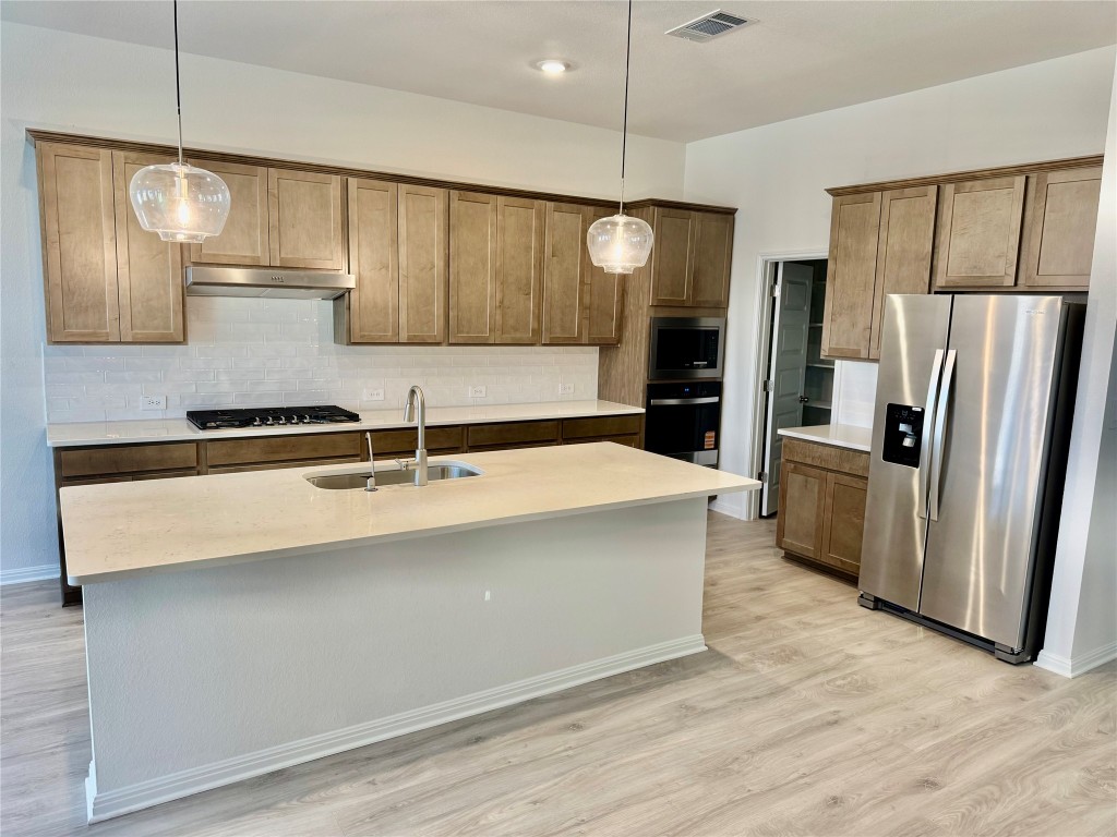 1764 South Main Street Kyle, TX 78640 - Photo 2 of 7 a kitchen with stainless steel appliances a refrigerator a sink and wooden cabinets