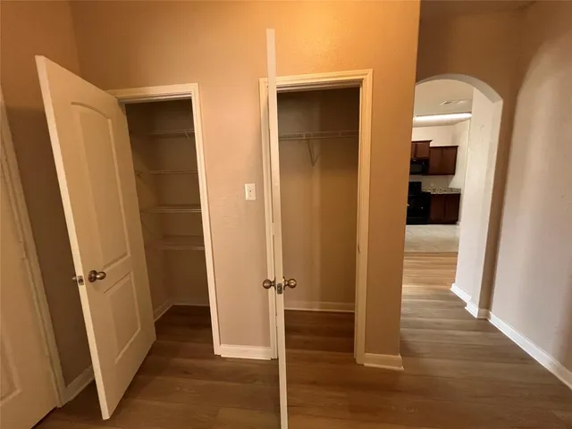 a view of a hallway with wooden floor and closet area