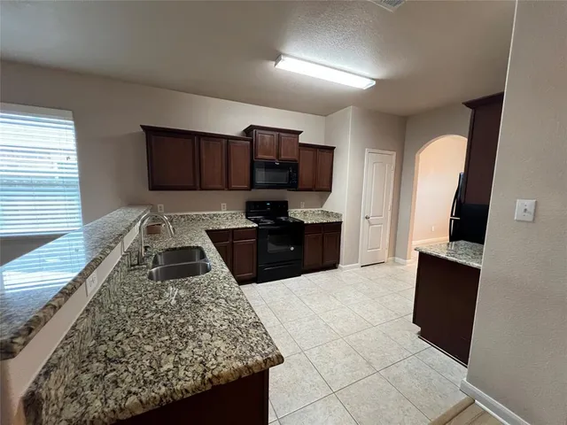 a kitchen with granite countertop a stove refrigerator and microwave