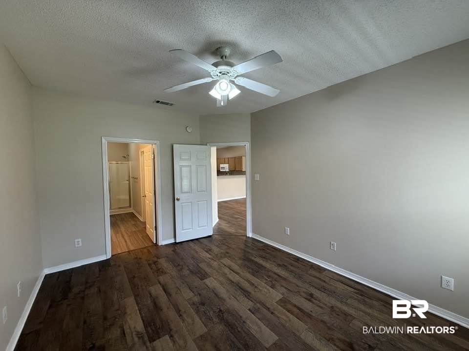 2651 South Juniper Street, Unit 401 Foley, AL 36535 - Photo 24 of 27 Unfurnished bedroom with a textured ceiling, visible vents, dark wood finished floors, and baseboards