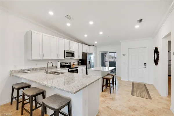 a kitchen with kitchen island granite countertop a table chairs microwave and cabinets