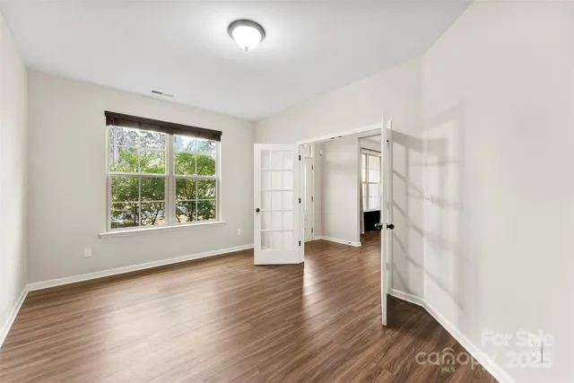 an empty room with wooden floor and windows