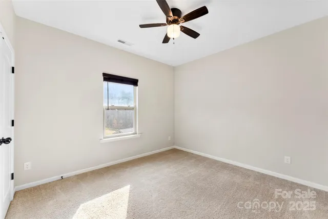 an empty room with a window and a fan