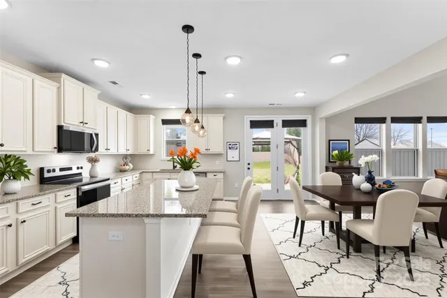 a view of a dining room with furniture a kitchen and chandelier