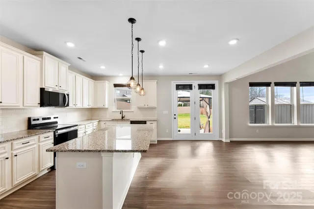 a kitchen with stainless steel appliances granite countertop a stove top oven a sink dishwasher a refrigerator and cabinets with wooden floor