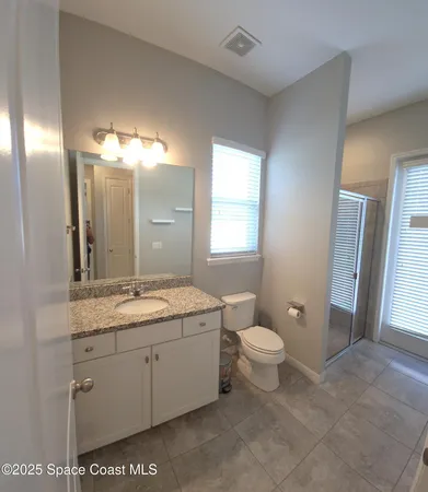 a bathroom with a granite countertop sink a toilet and a mirror