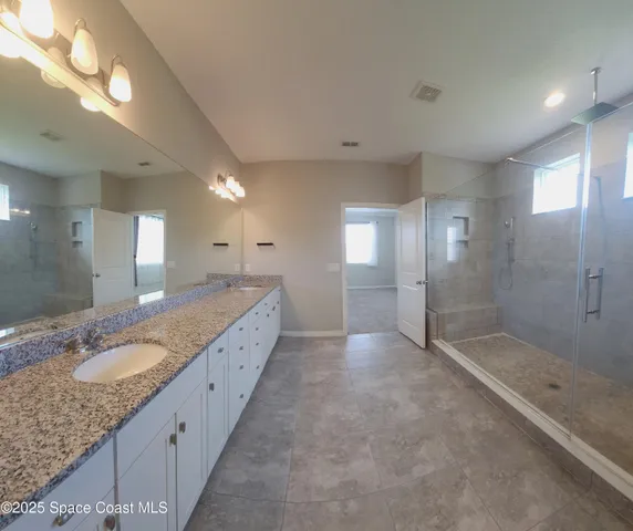 a bathroom with a granite countertop double vanity sink and mirror