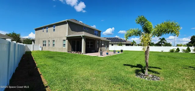 a view of a house with backyard and a tree
