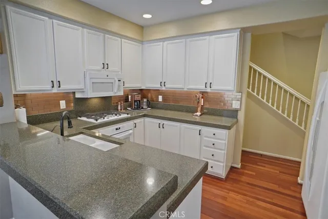 a kitchen with granite countertop a sink a stove and cabinets