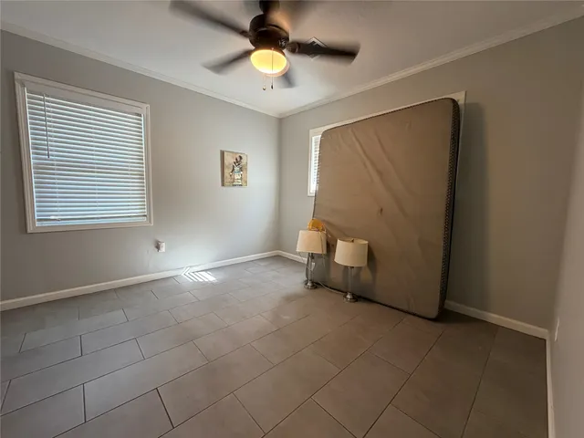 a view of an empty room with window and chandelier fan