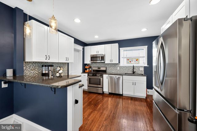 a kitchen with stainless steel appliances granite countertop a refrigerator a stove top oven a sink and dishwasher with wooden floor