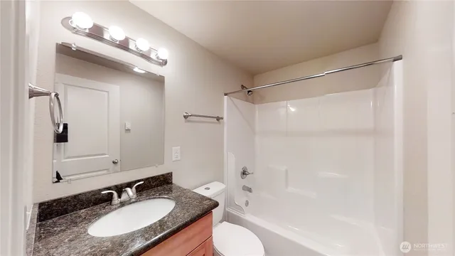 a bathroom with a granite countertop sink toilet a mirror a vanity and shower