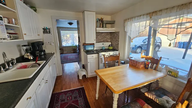 a living room with stainless steel appliances furniture a rug kitchen view and a large window